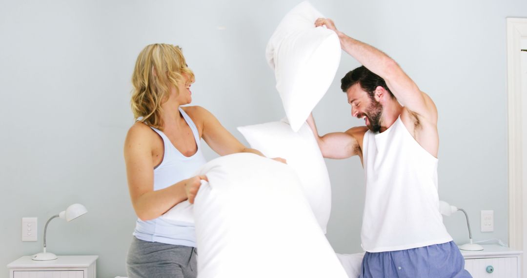 Happy Couple Having Pillow Fight in Bright Bedroom - Free Images, Stock Photos and Pictures on Pikwizard.com