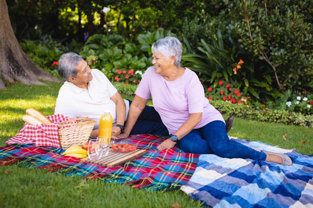 Biracial senior couple relax on park blankets, smiling at each other against plants - Free Images, Stock Photos and Pictures on Pikwizard.com