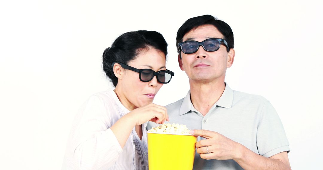 Elderly Asian Couple Watching 3D Movie and Eating Popcorn - Free Images, Stock Photos and Pictures on Pikwizard.com