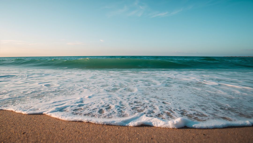 Turquoise Wave Lapping Sandy Shoreline During Golden Hour Foamy Surf Tranquil Coast