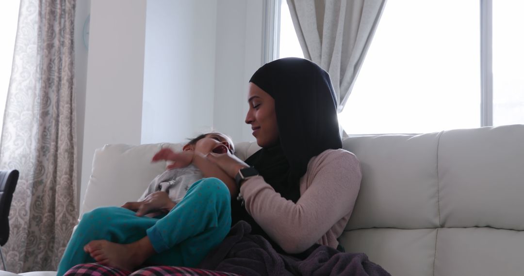 Mother in Hijab Bonding with Daughter on Sofa