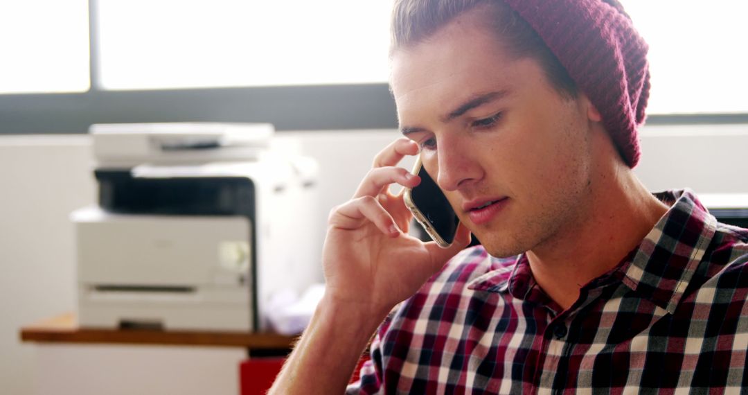 Young man talking on phone in modern office - Free Images, Stock Photos and Pictures on Pikwizard.com