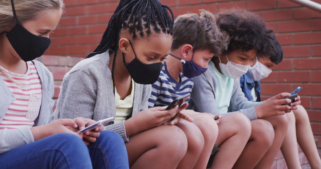 Diverse Group of Kids Wearing Face Masks Using Smartphones Outdoors - Free Images, Stock Photos and Pictures on Pikwizard.com