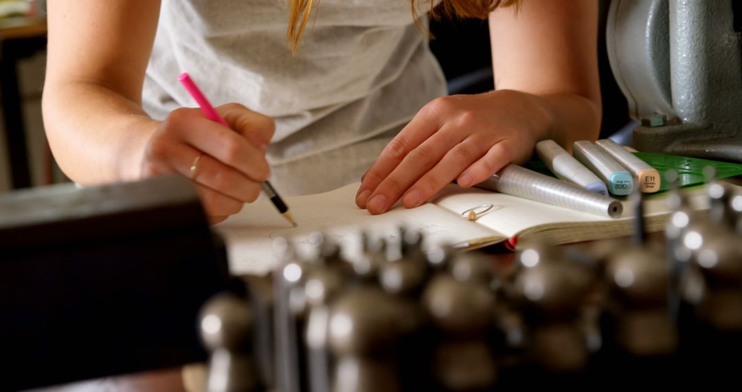 Woman Writing Notes in Journal with Stationery in Workshop - Free Images, Stock Photos and Pictures on Pikwizard.com