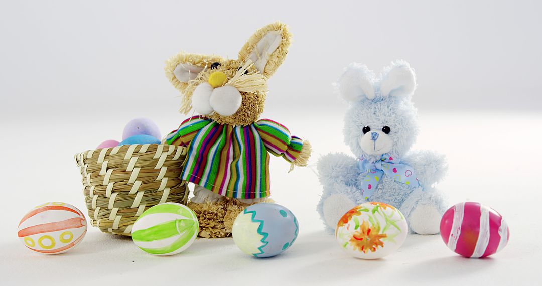 A festive Easter display features two plush bunnies beside a basket of vibrant eggs. - Free Images, Stock Photos and Pictures on Pikwizard.com