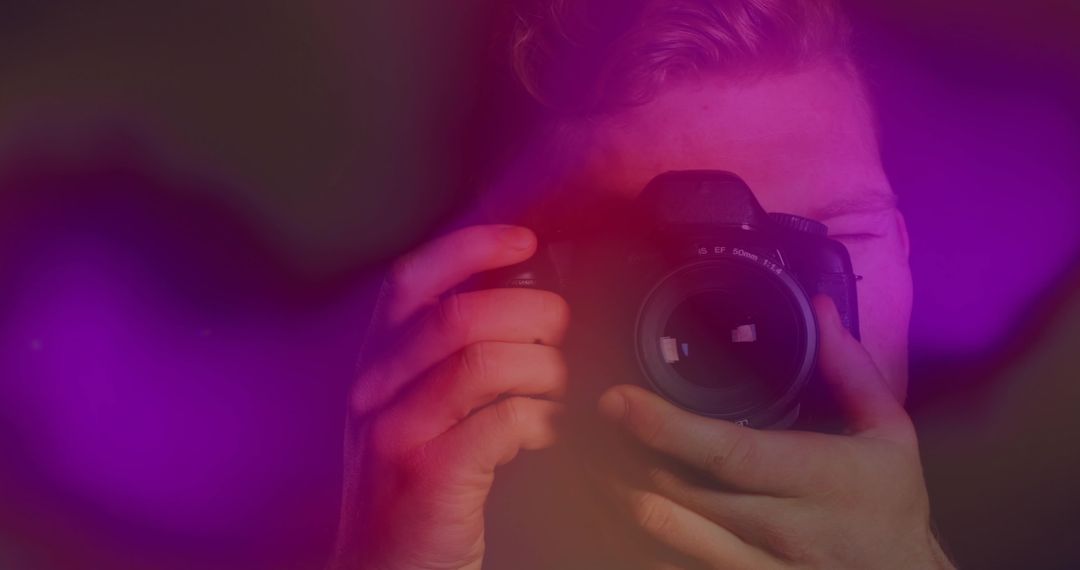 Photographer with DSLR Holding Viewfinder Amid Purple Red Bokeh Lights