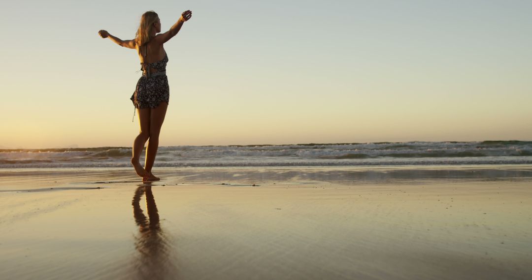 Woman Enjoying Sunset on Beach with Arms Outstretched - Free Images, Stock Photos and Pictures on Pikwizard.com
