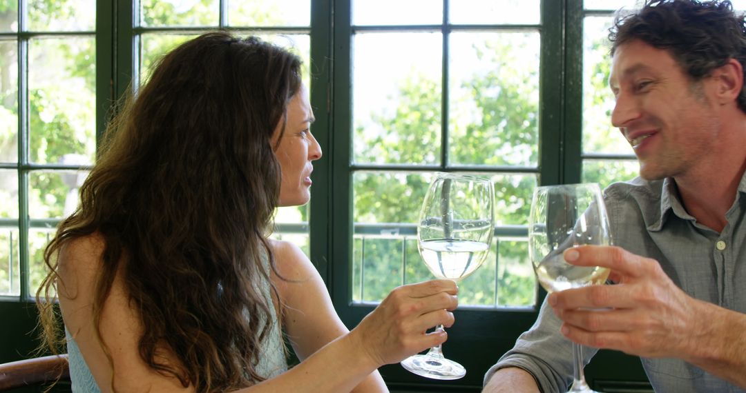 Joyful Couple Toasting with White Wine in Restaurant