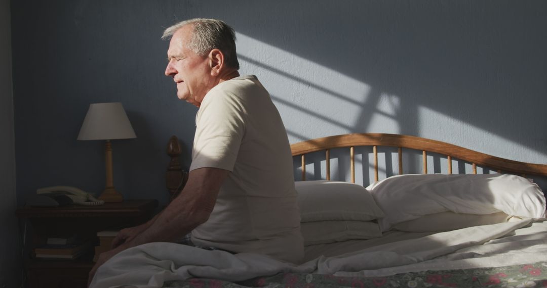 Elderly Man Sitting on Bed in Sunlit Bedroom - Free Images, Stock Photos and Pictures on Pikwizard.com