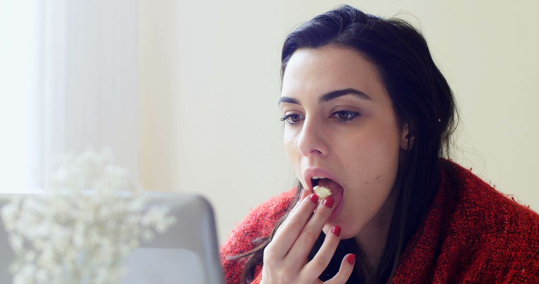 A young Caucasian woman is eating while focused on her laptop screen, with copy space - Free Images, Stock Photos and Pictures on Pikwizard.com