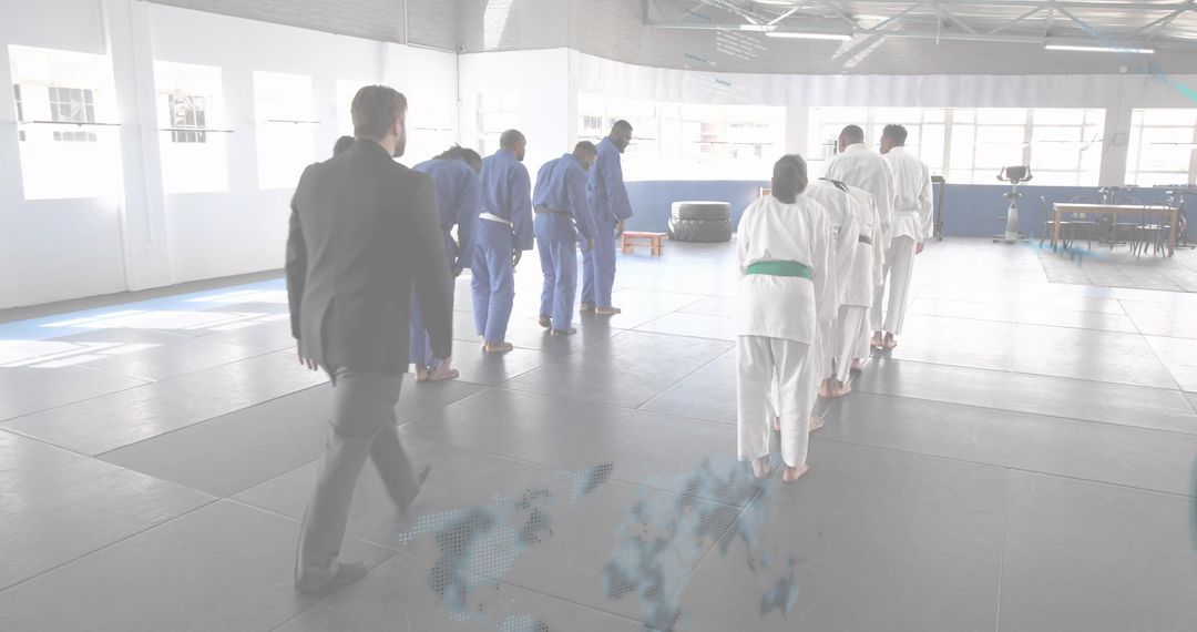 Instructor in Suit Walking Toward Bowing Martial Artists in Dojo Training and Discipline
