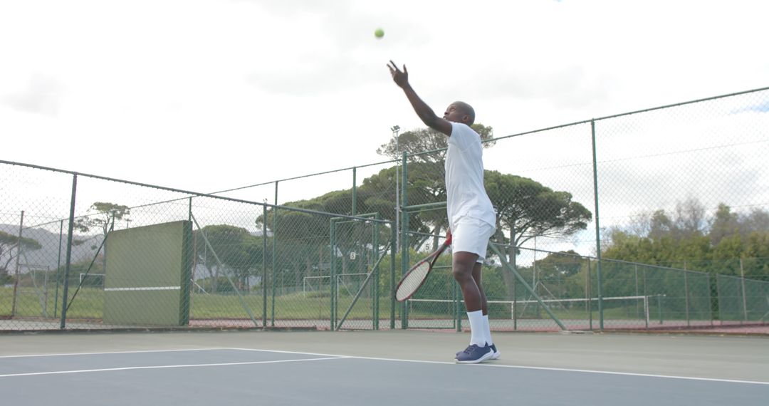 Tennis Player Serving Ball on Outdoor Court Under Clear Sky - Free Images, Stock Photos and Pictures on Pikwizard.com