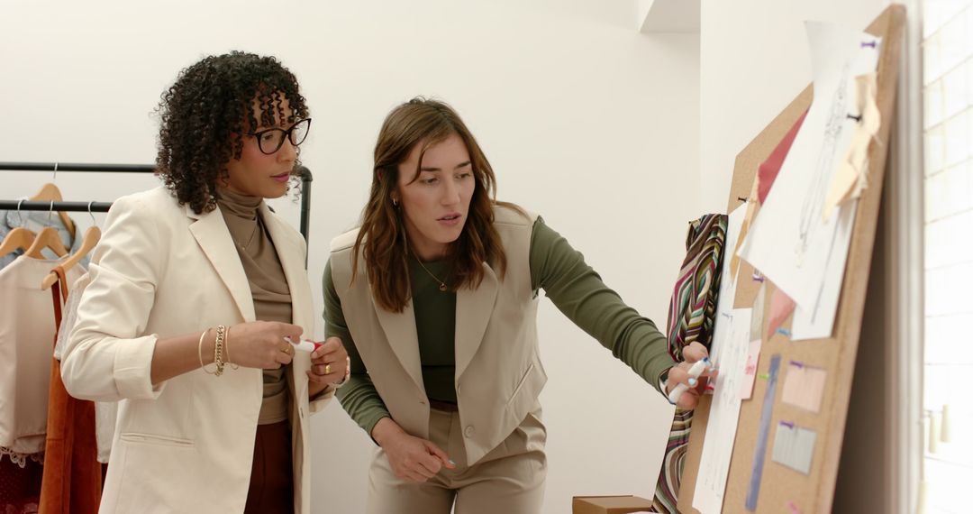 Female Fashion Designers Collaborating on Moodboard with Fabric Swatches and Sketches