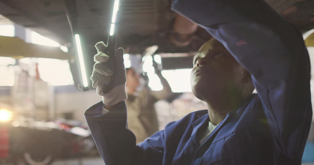 Auto Mechanic in Garage Emphasizing Precise Under-Car Repair