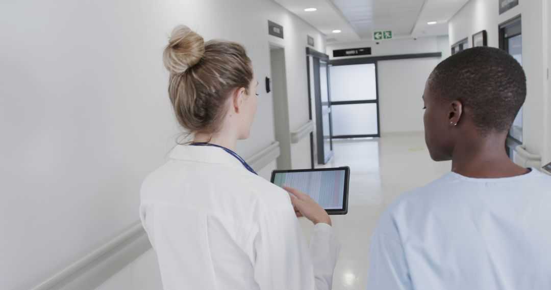 Doctor Using Tablet to Speak with Patient in Hospital Corridor - Free Images, Stock Photos and Pictures on Pikwizard.com