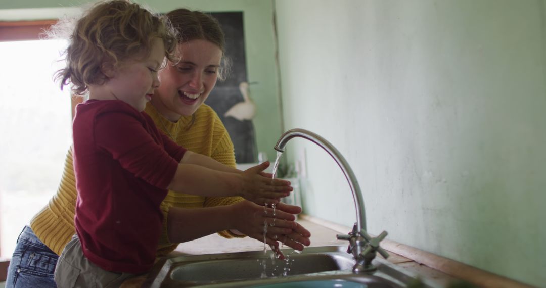 Smiling Mother Teaching Child to Wash Hands in Kitchen - Free Images, Stock Photos and Pictures on Pikwizard.com