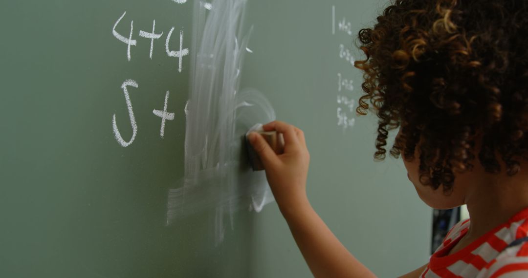 Young Boy Erasing Math Equations on Classroom Chalkboard
