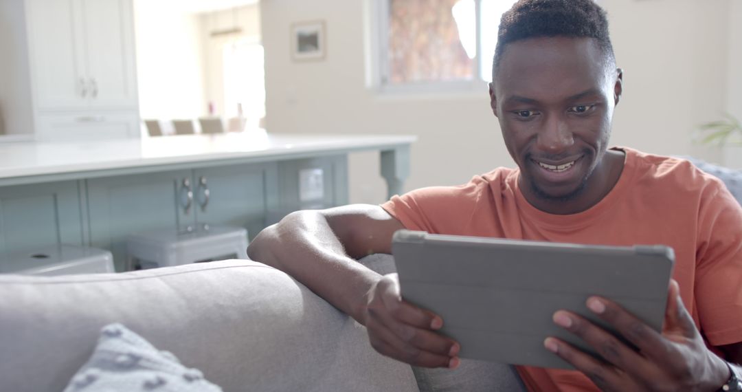 Smiling man using digital tablet in modern living room - Free Images, Stock Photos and Pictures on Pikwizard.com