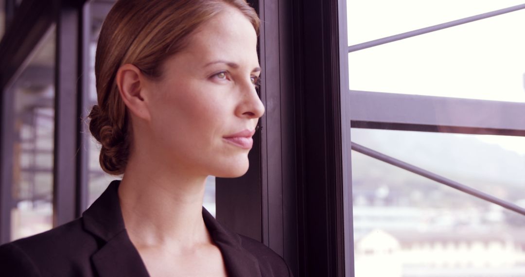 Confident Professional Woman Near Office Window with Contemplative Expression - Free Images, Stock Photos and Pictures on Pikwizard.com