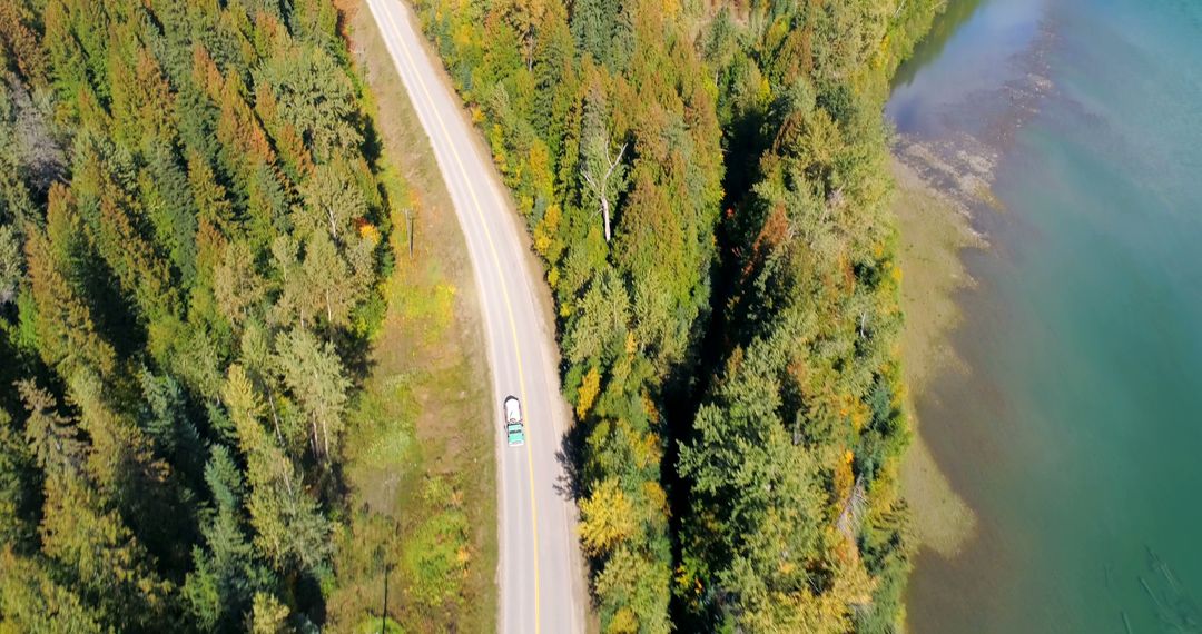 Aerial View of Curving Road Through Dense Forest by Serene Lake - Free Images, Stock Photos and Pictures on Pikwizard.com