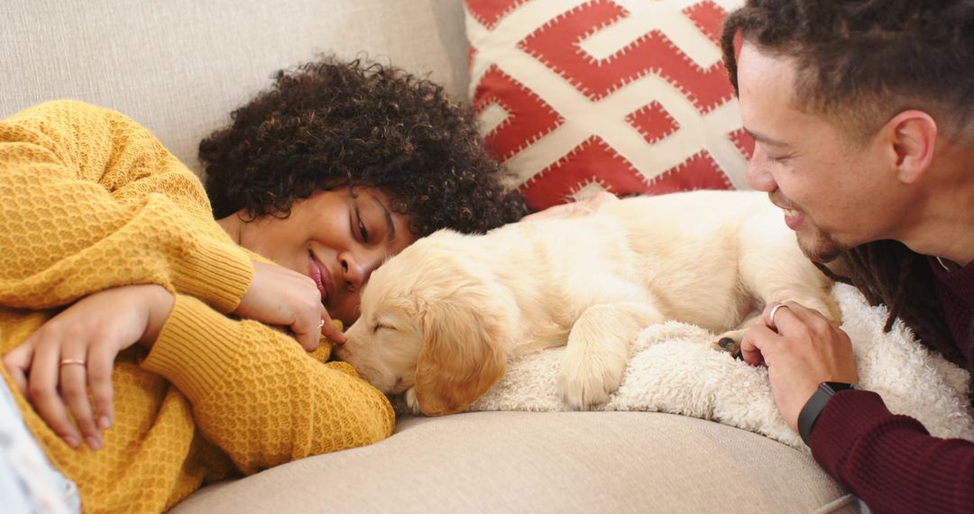 Cuddling golden retriever puppy on couch with diverse couple, cozy home bonding moment
