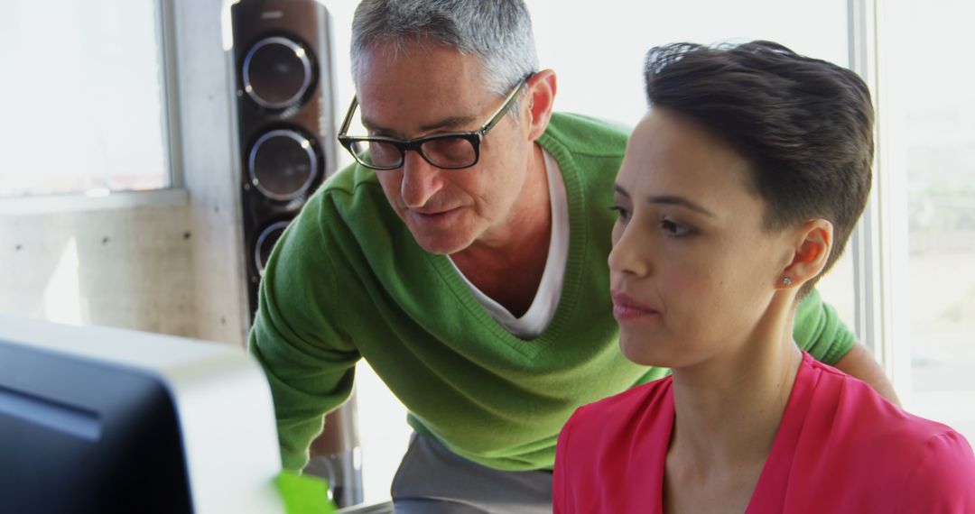 Colleagues Collaborating Over Computer at Office Desk