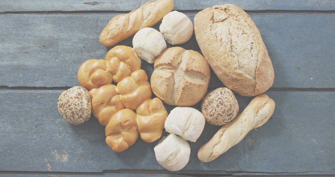 Displaying rustic artisan breads and crusty rolls on weathered blue-gray board, flatlay