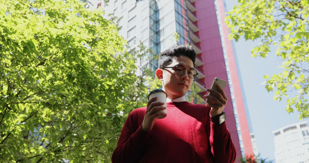 Young Man Holding Coffee Cup and Smartphone Outdoors - Free Images, Stock Photos and Pictures on Pikwizard.com