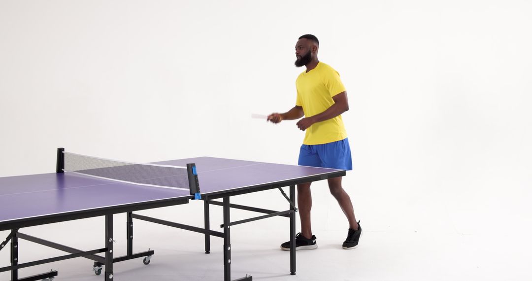 Man Playing Table Tennis Enthusiastically in Modern Studio
