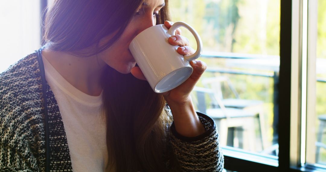 Young Woman Sipping Coffee by Window in Bright Morning Light - Free Images, Stock Photos and Pictures on Pikwizard.com