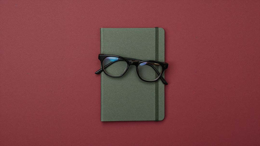 Olive Green Notebook with Eyeglasses on Burgundy Background