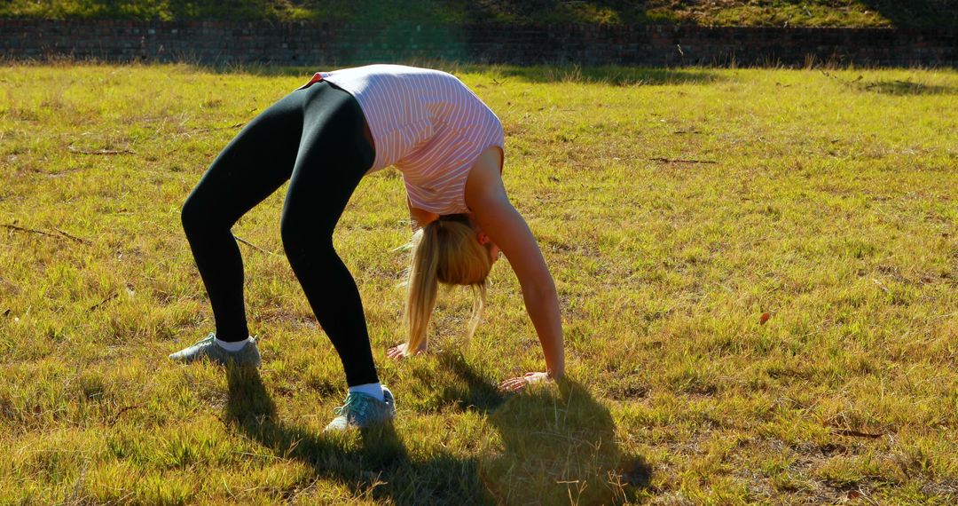 Woman Performing Stretching Exercise in Sunny Grassy Field - Free Images, Stock Photos and Pictures on Pikwizard.com