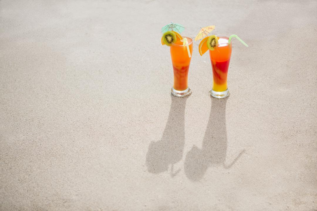 Overhead view of two glasses of cocktail drink kept on sand - Free Images, Stock Photos and Pictures on Pikwizard.com