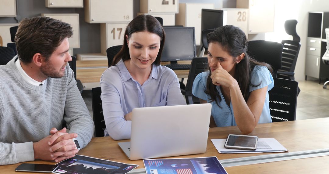 Diverse Professionals Collaborating Over Laptop in Modern Office