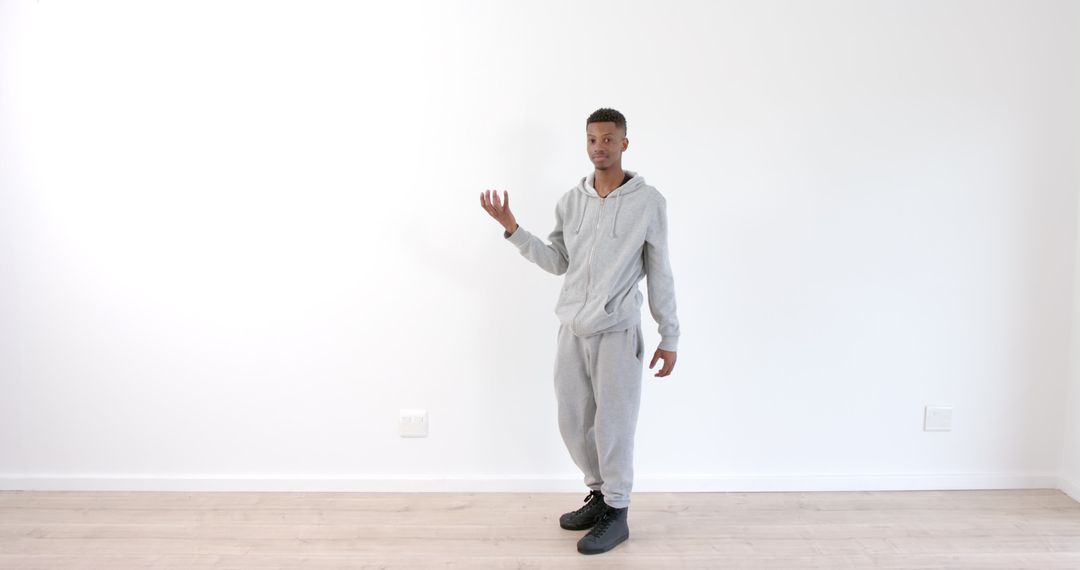 Man in Gray Tracksuit Performing Mime Against White Wall