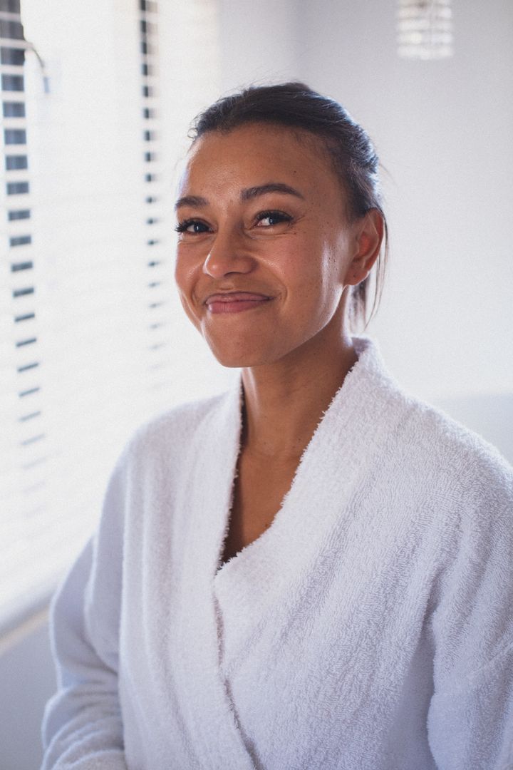 Portrait of biracial woman wearing bathrobe looking to camera and smiling - Free Images, Stock Photos and Pictures on Pikwizard.com