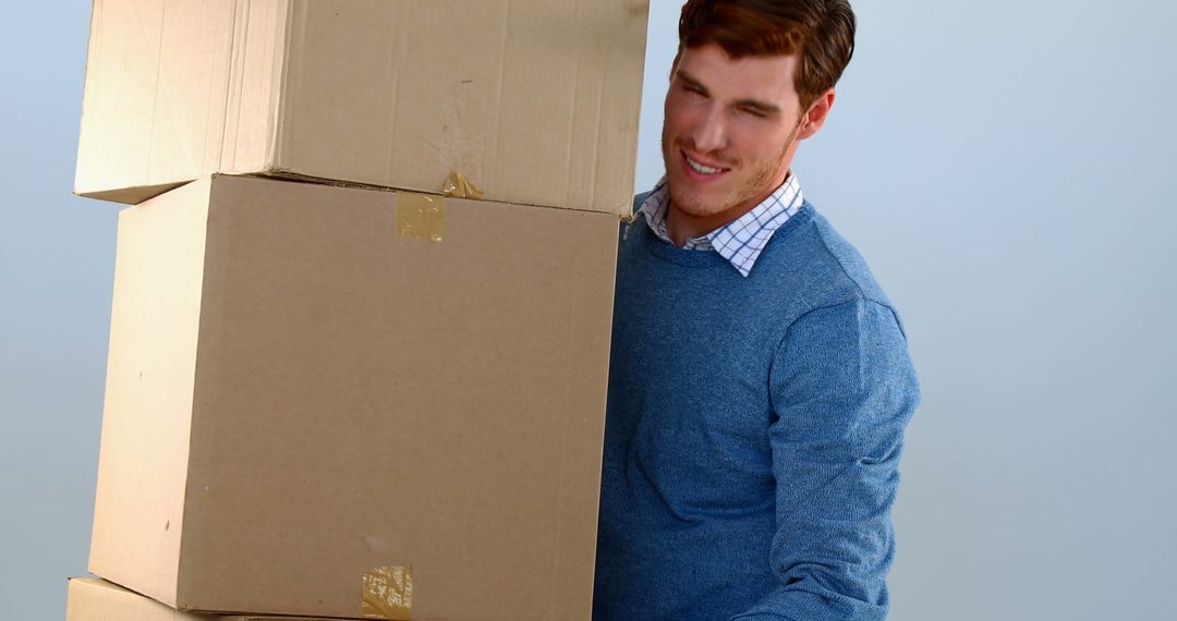 Man Lifting Cardboard Boxes with Effort and Smiling