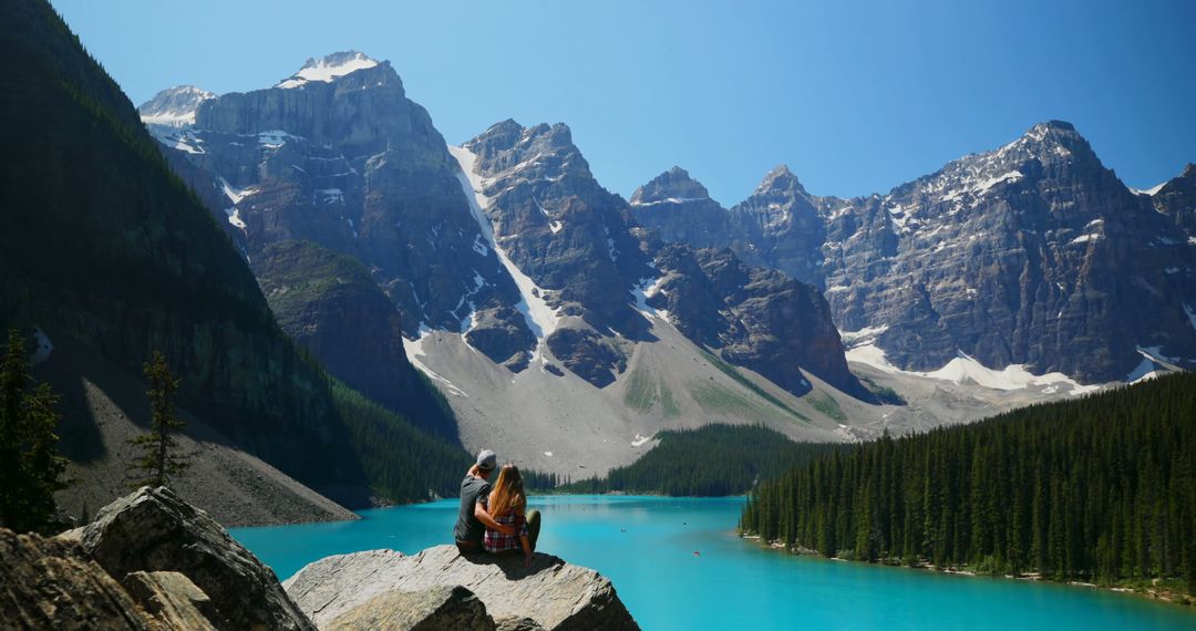 Couple Enjoying Mountain View by Turquoise Lake in Rocky Mountains - Free Images, Stock Photos and Pictures on Pikwizard.com