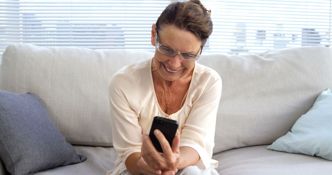 Senior Woman Smiling While Using Smartphone in Living Room - Free Images, Stock Photos and Pictures on Pikwizard.com