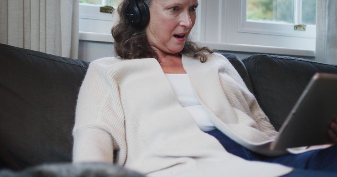 Middle-aged woman wearing headphones, reacting to tablet content - Free Images, Stock Photos and Pictures on Pikwizard.com