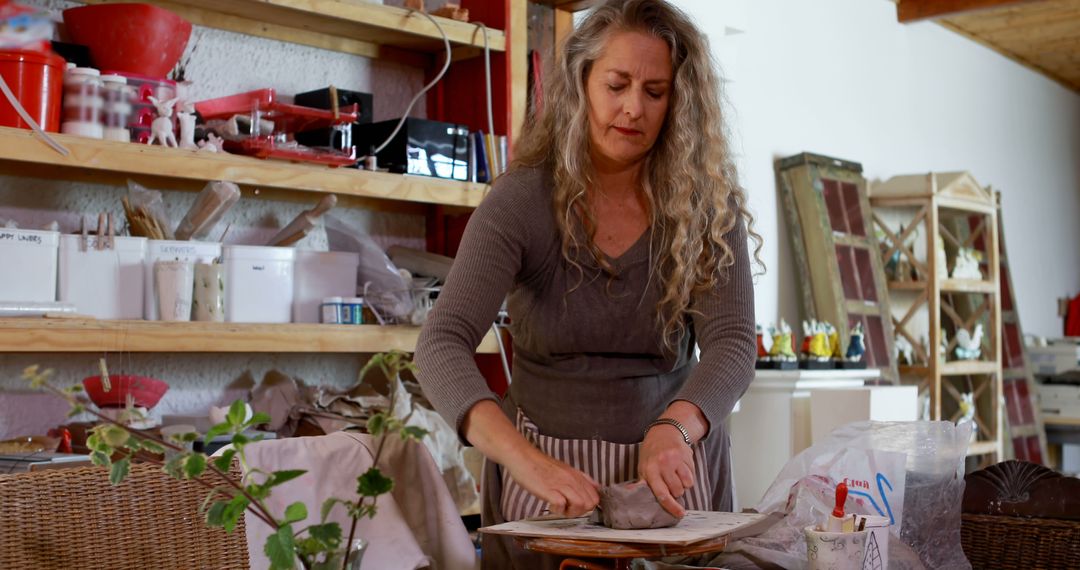 Woman Sculpting Clay in Art Studio with Shelves of Supplies - Free Images, Stock Photos and Pictures on Pikwizard.com