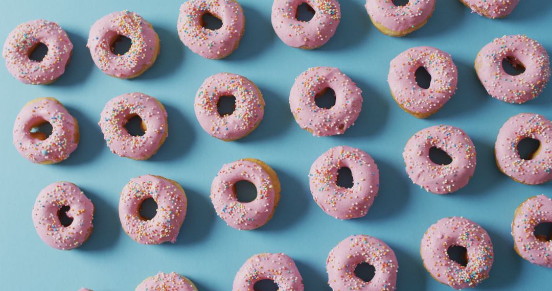 Rows of Pink Iced Donuts with Sprinkles on Blue Background - Free Images, Stock Photos and Pictures on Pikwizard.com