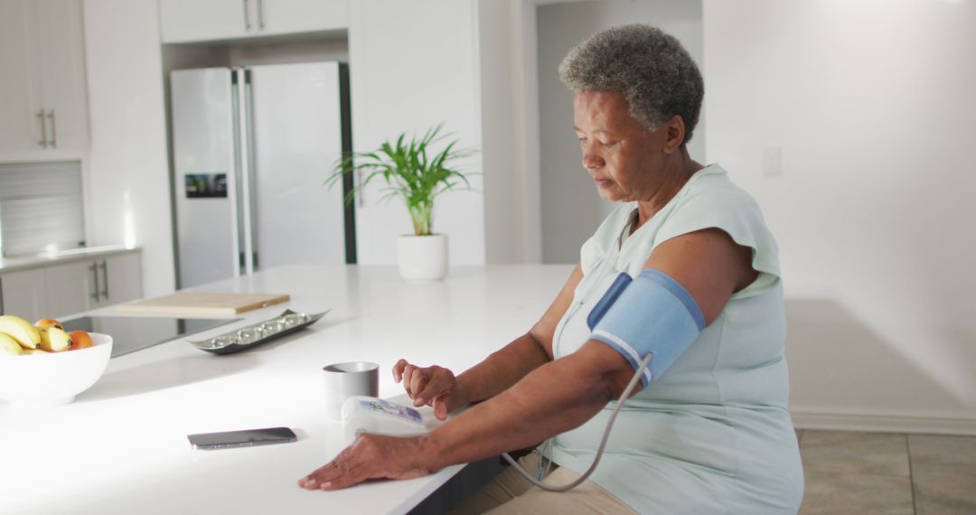 Senior Woman Measuring Blood Pressure in Modern Kitchen - Free Images, Stock Photos and Pictures on Pikwizard.com