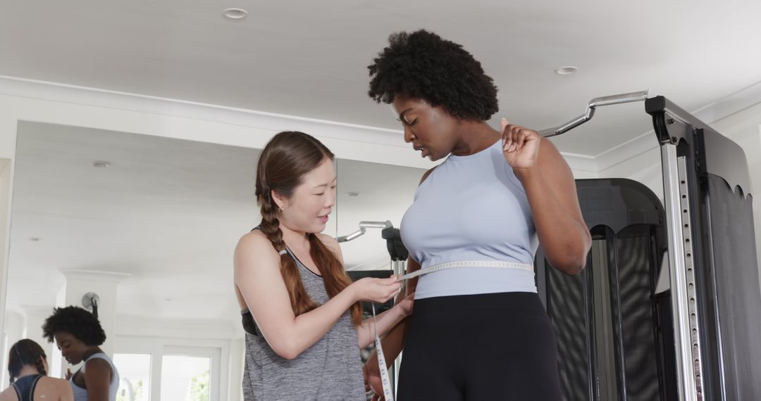 Fitness Trainer Measuring Waist of Smiling Woman at Gym