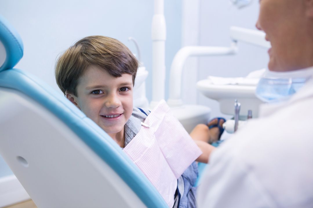 Portrait of cute boy sitting on dentist chair by dentist - Free Images, Stock Photos and Pictures on Pikwizard.com