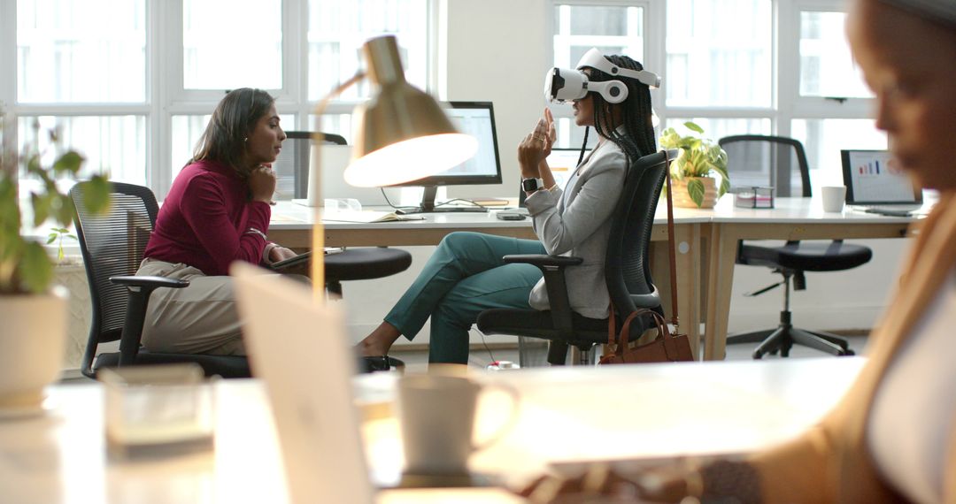 Female professionals demonstrating virtual reality collaboration in modern open-plan office