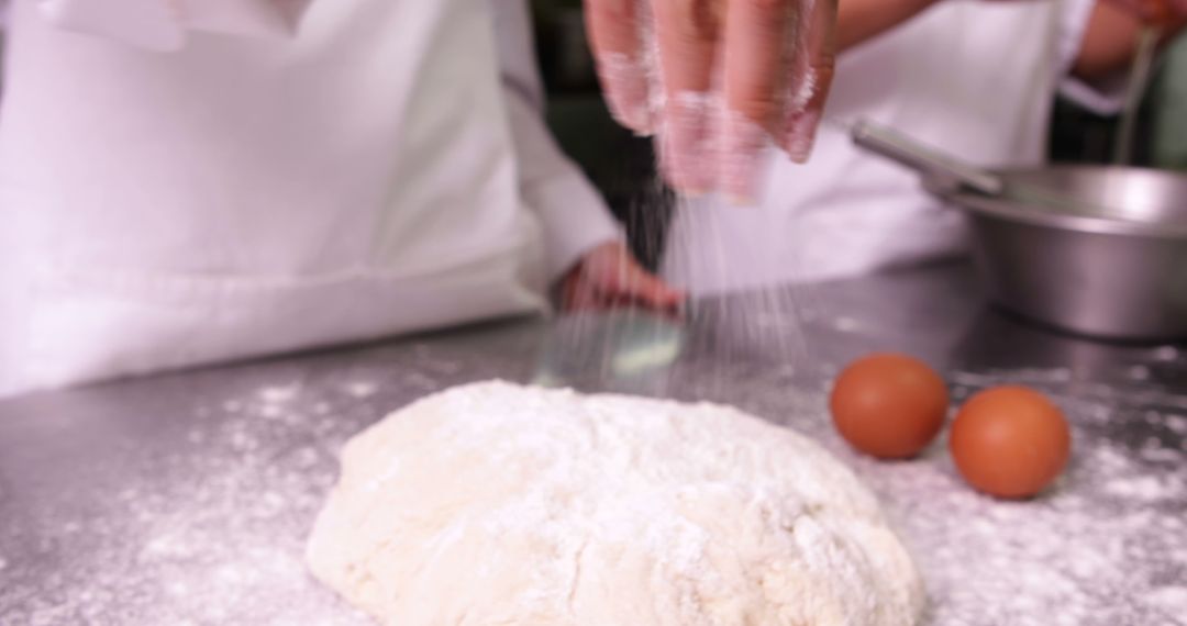 Baker's hands sprinkling flour on dough in kitchen - Free Images, Stock Photos and Pictures on Pikwizard.com