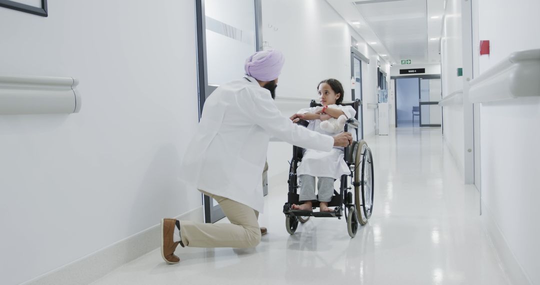 Doctor comforting child in wheelchair in hospital corridor - Free Images, Stock Photos and Pictures on Pikwizard.com