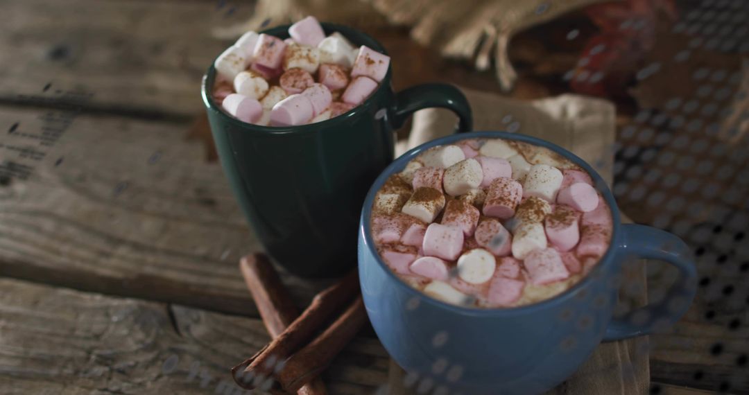 Cozy rustic mugs steaming hot cocoa overflowing with pink marshmallows and cinnamon sticks