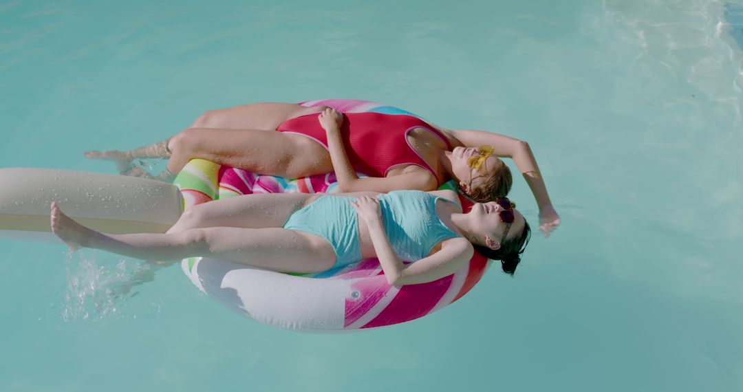 Friends Relaxing on Inflatable Donut in Turquoise Pool